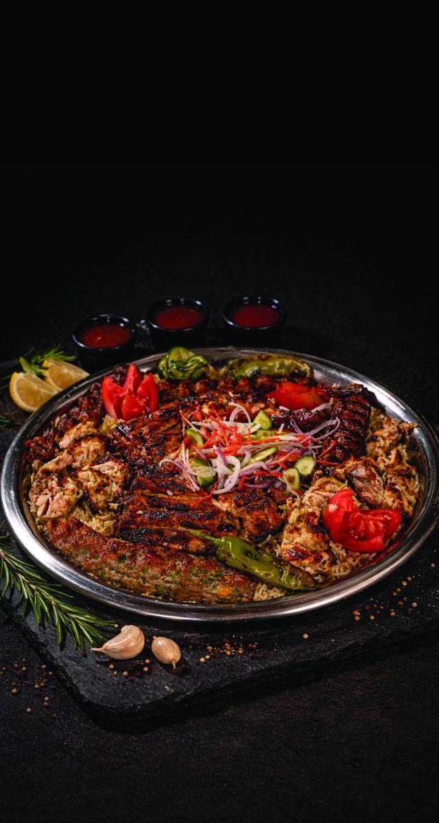 Sufraq BBQ Feast Platter with flame-grilled kebabs and boti over seasoned rice