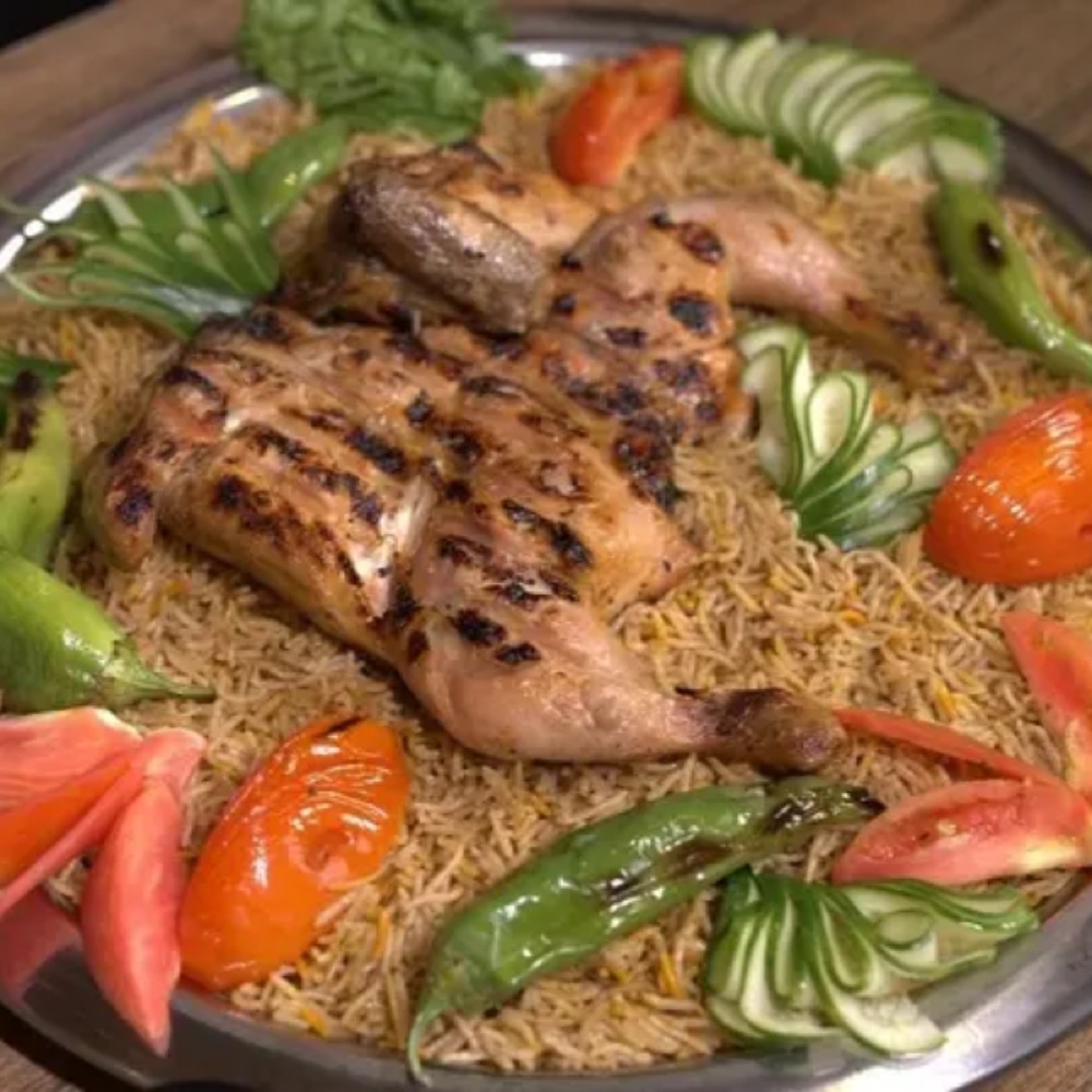 A Sufraq grilled chargha platter brought to the centre of the table, with seasoned rice and signature sauces